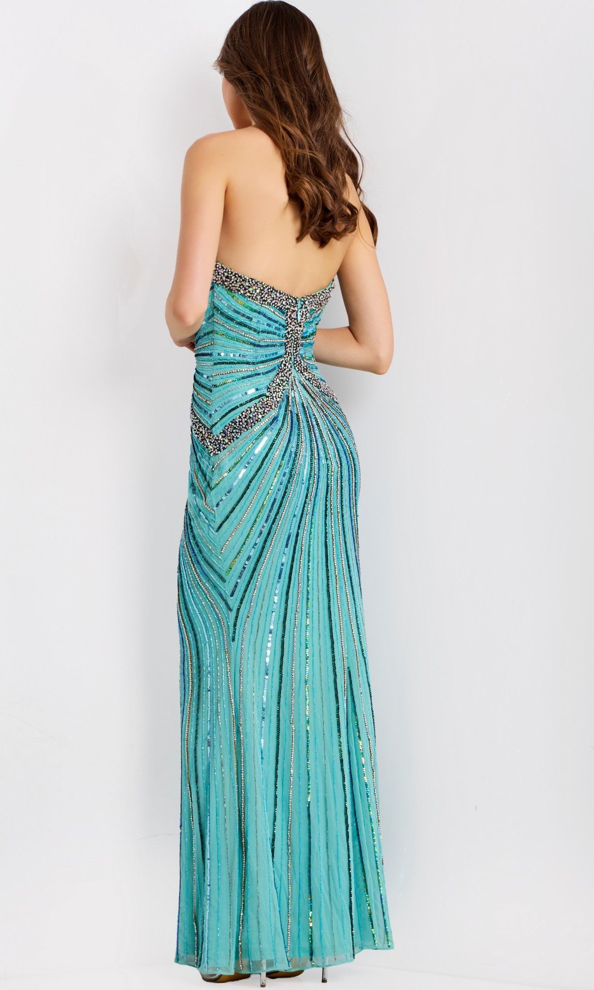 A woman in the Jovani 49224 long prom dress—a strapless, floor-length turquoise evening gown with sequins and beadwork—stands facing away from the camera against a plain white background.